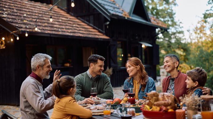 Happy extended family talking while celebrating Thanksgiving on the patio.
