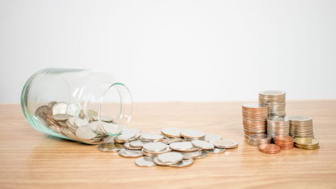 Glass bottle, put a coin on a wooden table. And there are a lot of coins. Save money.