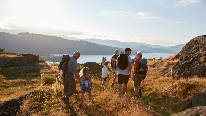 Rear View Of Multi Generation Family Walking On Top Of Hill On Hike Through Countryside In Lake District UK