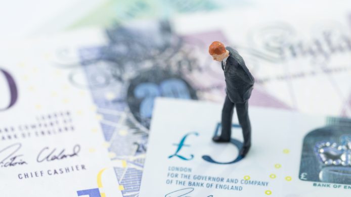 Miniature figure businessman leader standing and thinking on 5 pound sterling England currency banknotes, Brexit reconsider, UK economics, saving, financial or investment with Europe concept.