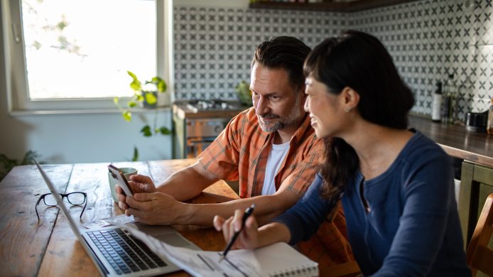 Couple managing bills with laptop on kitchen desk at home