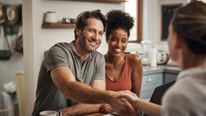 Love, handshake and couple with a financial advisor, consultation and discussion for investments. Partners, man and woman with a consultant, home and conversation for advice, help and shaking hands.